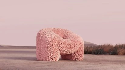 Pink textured armchair sculpture in surreal desert landscape, part of the New FuTure exhibition in Barcelona.