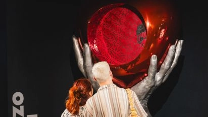 Visitors observing Lorenzo Quinn's metallic balloon sculpture with red heart at Moco Museum London
